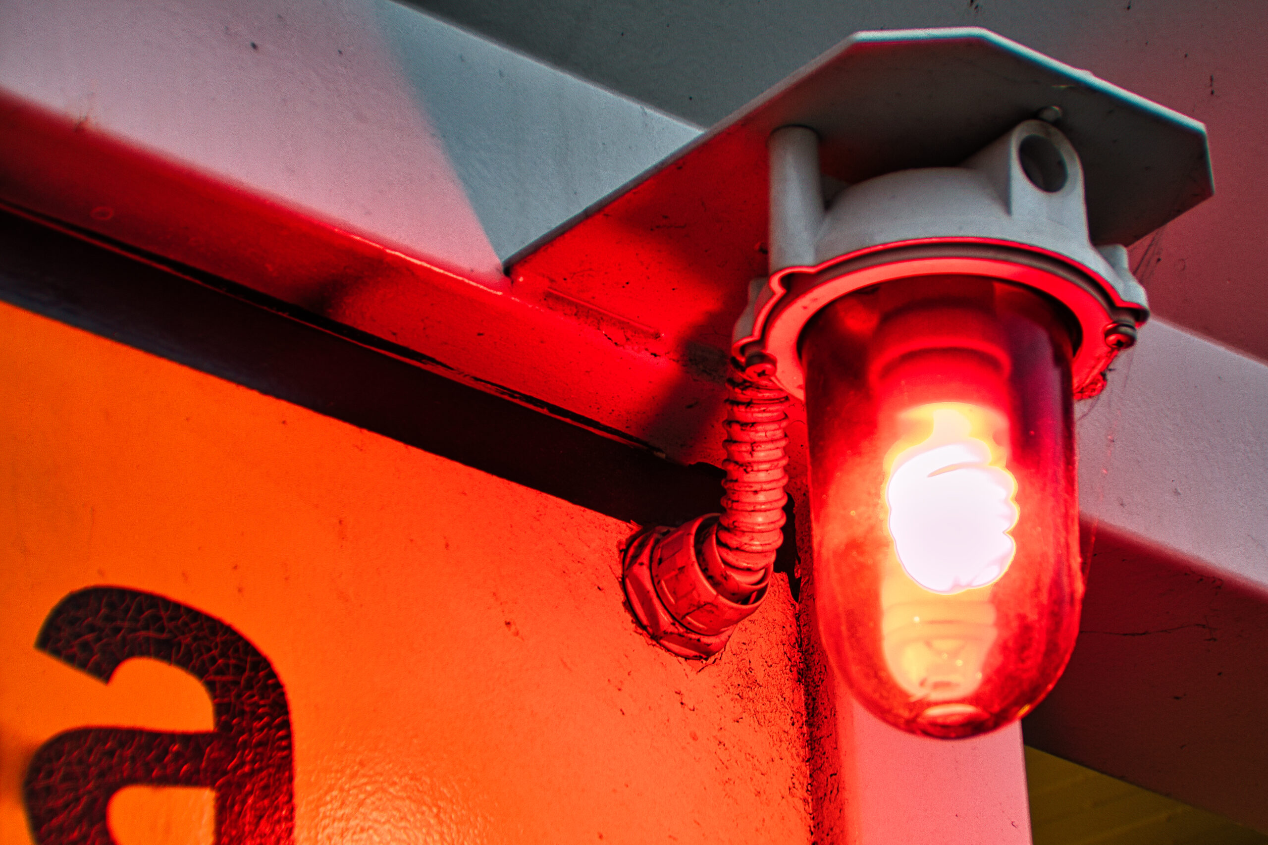 A closeup of a red warning light bulb on the wall