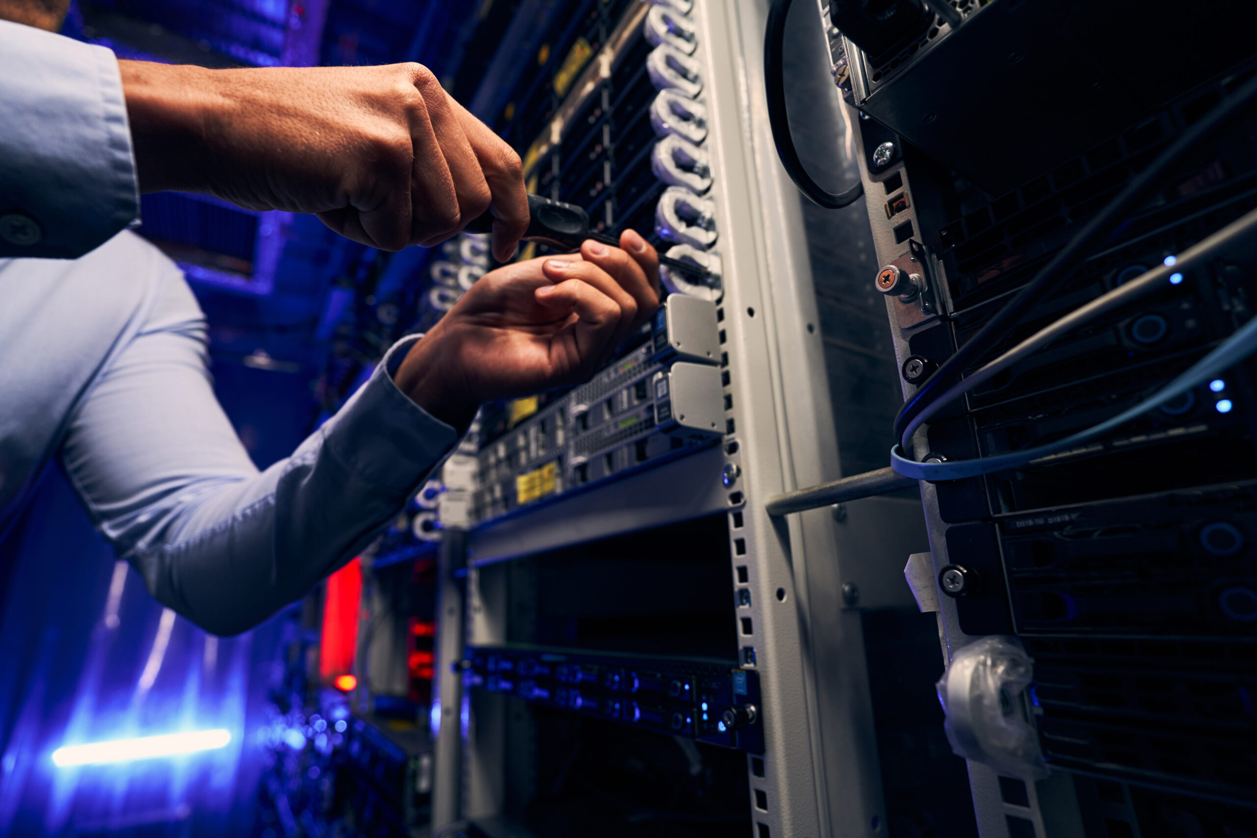 Cropped photo of data center engineer tightening screw on mounted hardware component using screwdriver