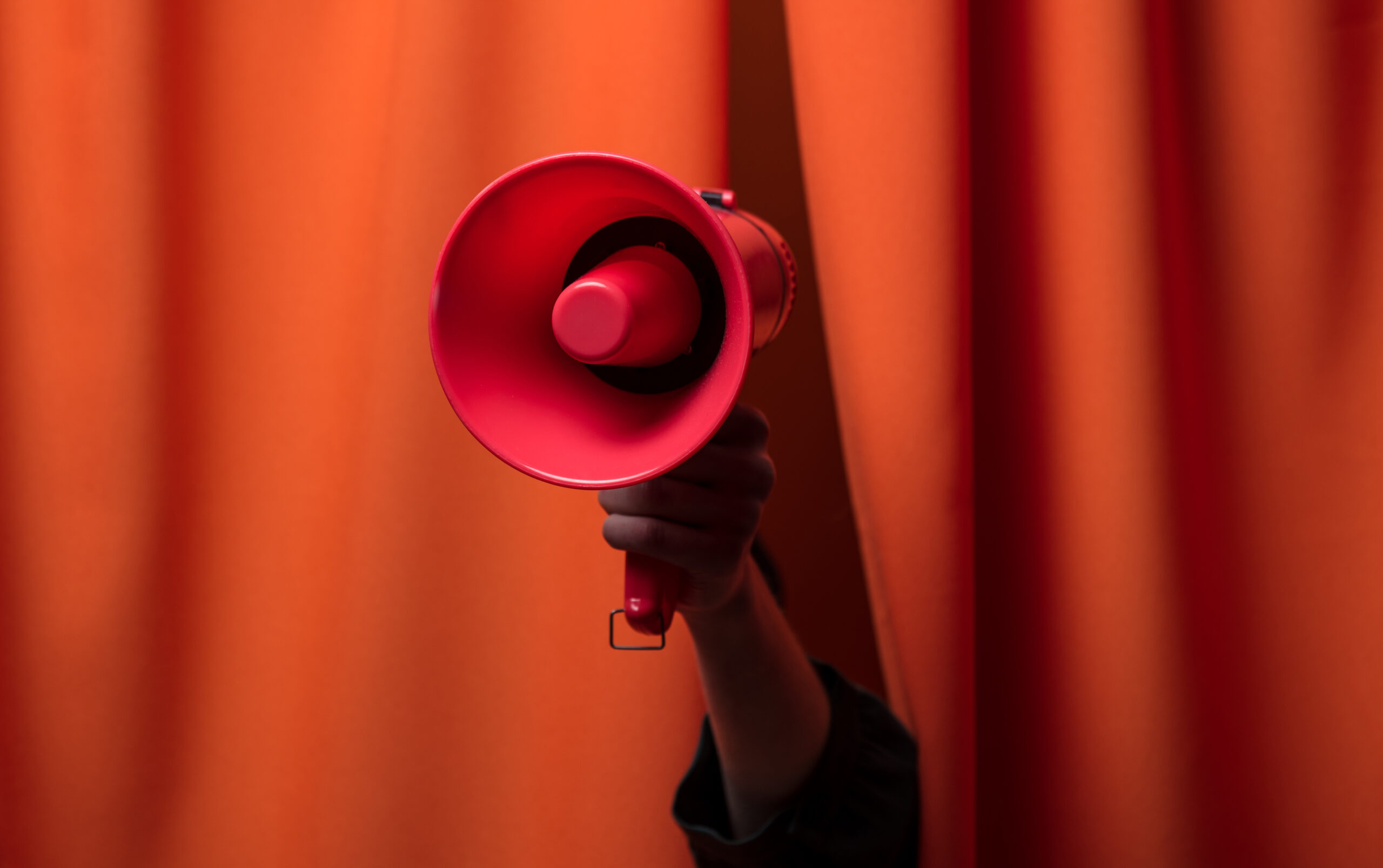 Hand hold megaphone on orange curtains background
