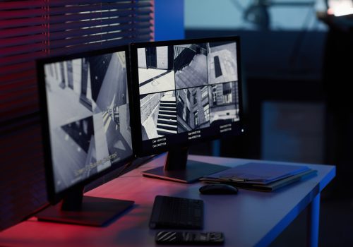Background image of computer screens with surveillance camera footage in dark room with blue and red tones
