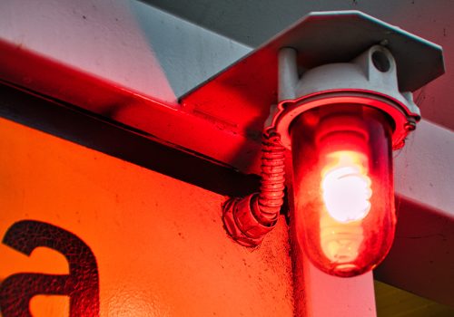 A closeup of a red warning light bulb on the wall