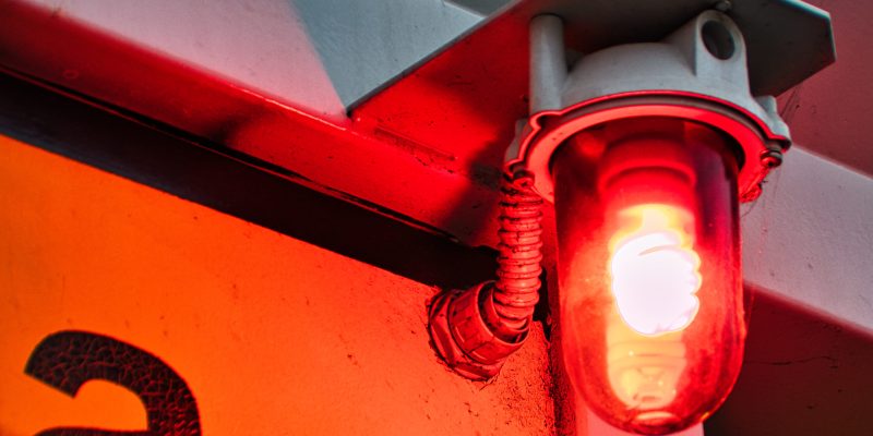 A closeup of a red warning light bulb on the wall