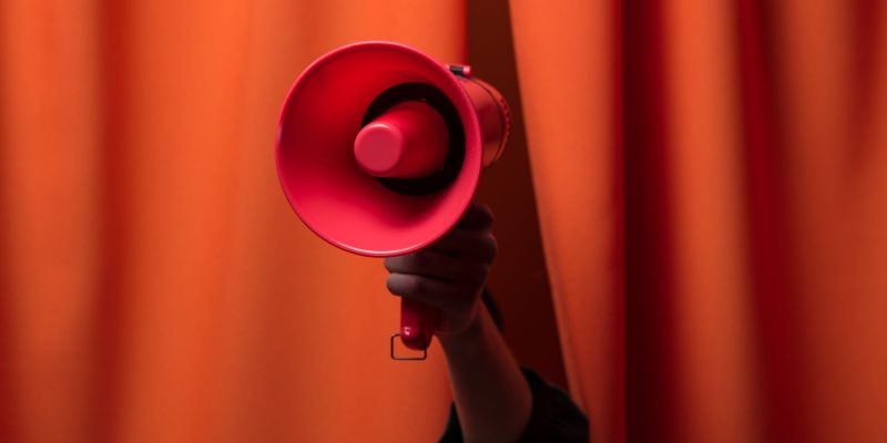 Hand hold megaphone on orange curtains background